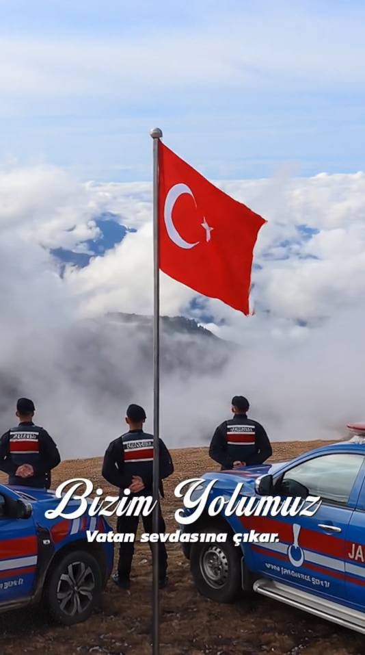 Bizim Yolumuz — trois gendarmes devant le drapeau, au-dessus des nuages